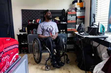 Kaelin sitting in a manual wheelchair looking out the window of his apartment.