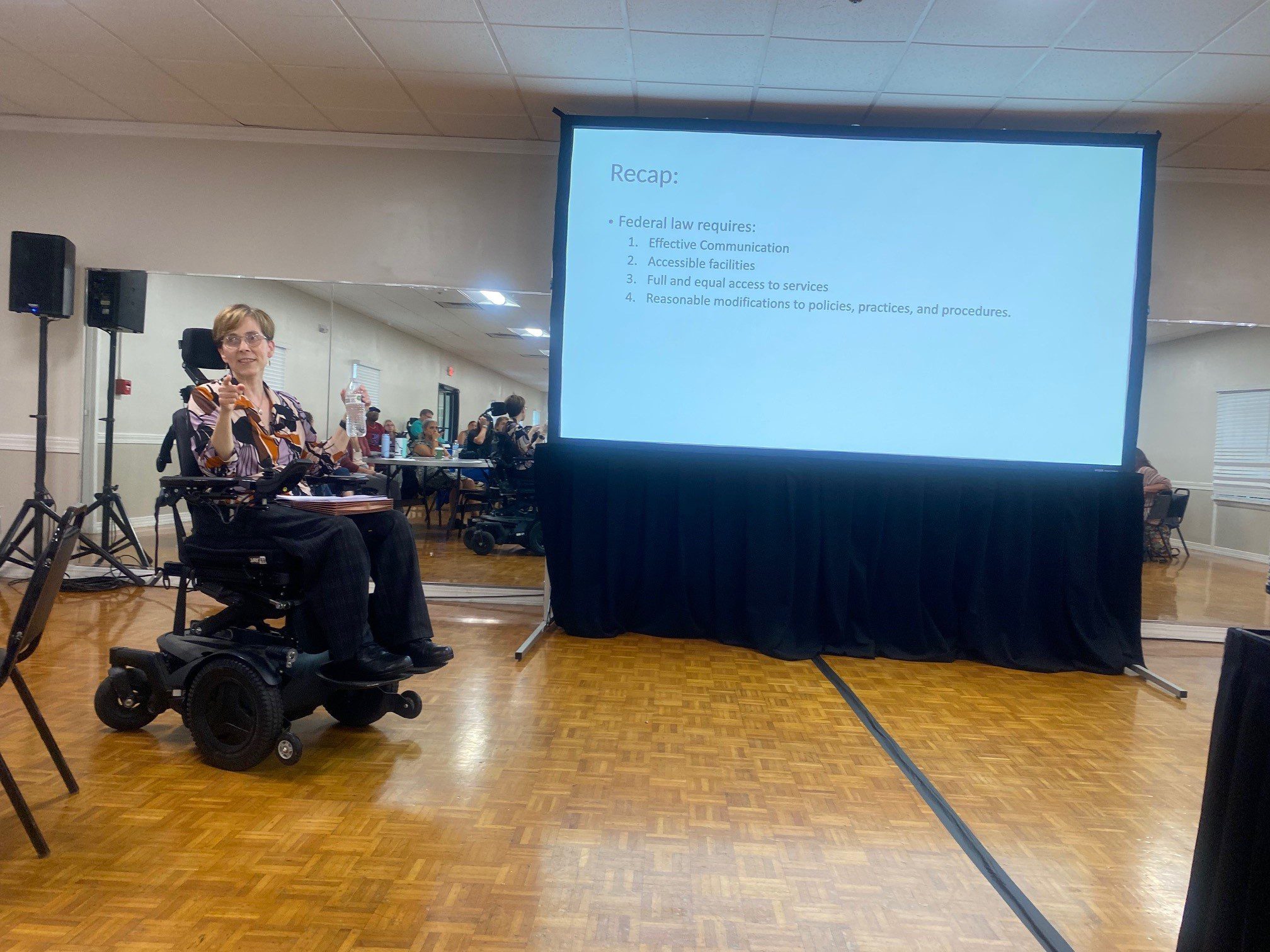 Jenny sitting in her wheelchair and speaking at the Kentucky Congress on SCI