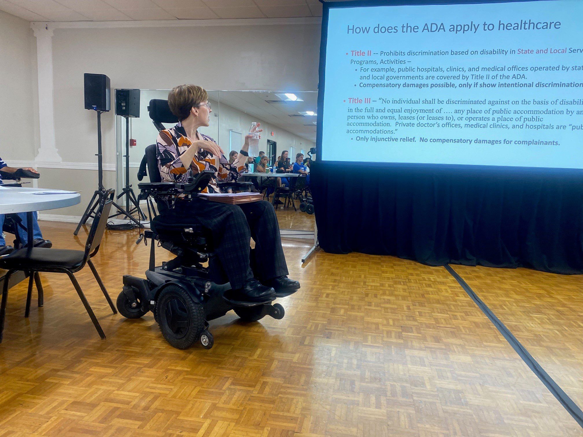 Jenny sitting in her wheelchair speaking at the Kentucky Congress on SCI