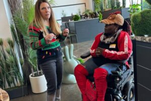 Two individuals chatting, one using a wheelchair with red boots, at the event.