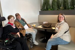 Liz Fust with two attendees seated, smiling and enjoying conversation.