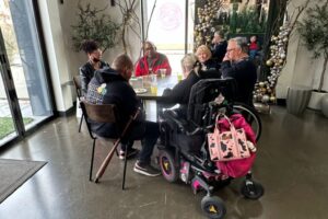 Group gathered around a table, chatting with holiday decorations in the background.