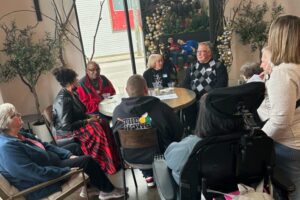 Group of attendees at a table with holiday decorations, engaged in conversation.