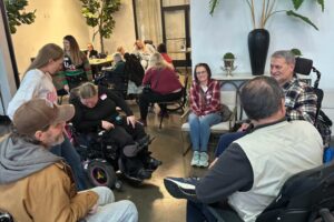 Several attendees in wheelchairs chatting and smiling together in a well-lit space.