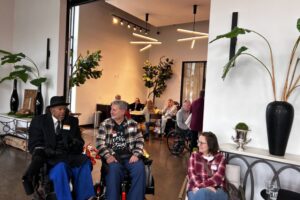 Three attendees, two using wheelchairs, talking and socializing.