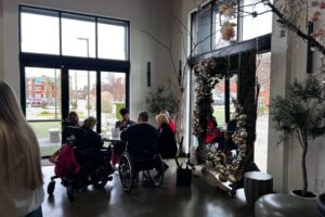 Wide view of the venue, showcasing festive decor, greenery, and attendees mingling.