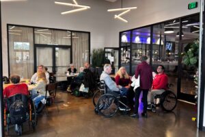 Guests seated at multiple tables enjoying conversations and refreshments in a lively venue.