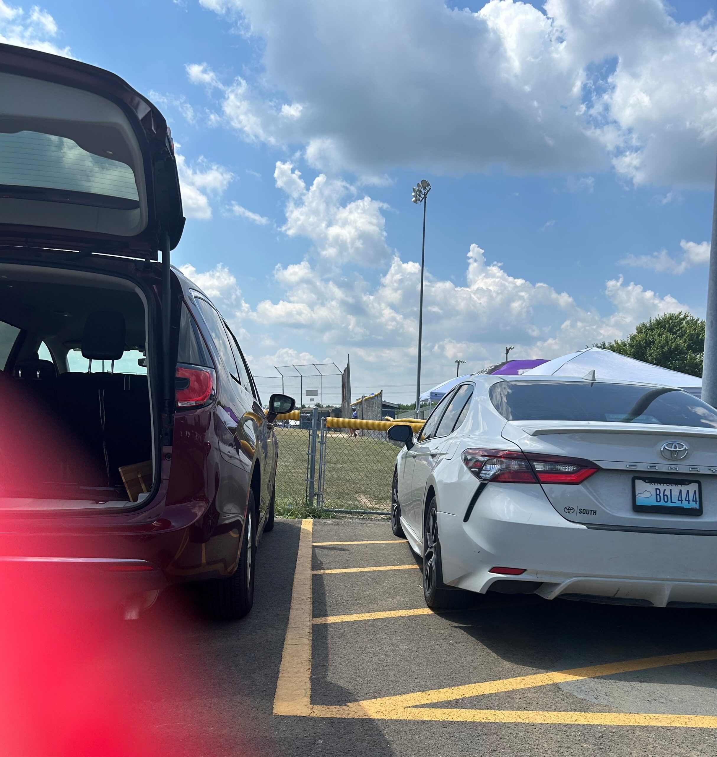 Lacey parked in 7-13-24 A white sedan is parked in the striped access aisle of a van-accessible parking place blocking the adapted van from deploying its ramp.