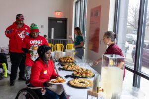 Three attendees and two volunteers smiling at a catering buffet line.