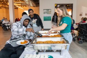 Event staff or volunteers organizing chafing dishes on a buffet table.
