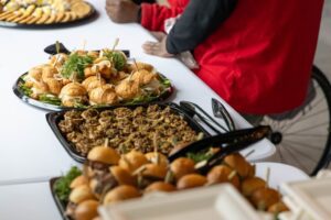 A close-up view of catered food, including sliders, in chafing dishes on a buffet line.