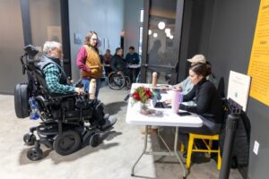 A wide view of attendees, including wheelchair users, arriving to an event space.