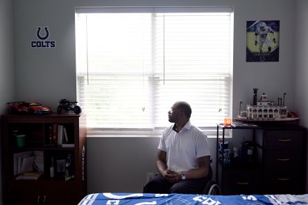 Terrell is a Black man sitting in a manual wheelchair in his bedroom and looking out the window.